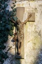 Beautiful rusty Jesus Christ crucifixion statue during sunset partly covered with common ivy, hedera helix on old wall Royalty Free Stock Photo