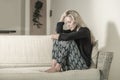 Beautiful 40s woman depressed at home - dramatic portrait of sad and desperate blonde girl on couch suffering depression problem