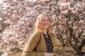 Beautiful 30s woman with long blonde hair posing between pink magnolia. Stunning girl looking at you or in camera. Royalty Free Stock Photo