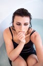 Beautiful sad brunette slender body in black dress and makeup sits in bathtub filled with water. Royalty Free Stock Photo