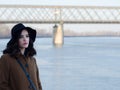 Beautiful sad girl in classic coat and hat beside river Royalty Free Stock Photo