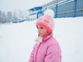 Beautiful sad girl 7 years old on a background of snow. A pink knitted hat and a pink warm jacket are worn by the child. Royalty Free Stock Photo