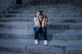 Beautiful and sad Hispanic woman desperate and depressed sitting on urban city street staircase