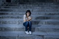 Beautiful and sad Hispanic woman desperate and depressed sitting on urban city street staircase