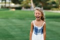 Beautiful sad little blonde curly hair girl crying  on summer background. Concept relationships with children and friendship in Royalty Free Stock Photo