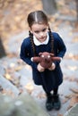 Beautiful sad little girl with with pigtails, dressed in dark blue standing near mystic abandoned building with gothic stairs and