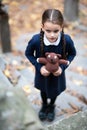 Beautiful sad little girl with with pigtails, dressed in dark blue standing near mystic abandoned building with gothic stairs and