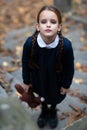 Beautiful sad little girl with with pigtails, dressed in dark blue standing near mystic abandoned building with gothic stairs and