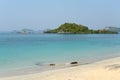 Beautiful sand beach and tropical sea at sunny summer day. Distant tropical island on the horizon.