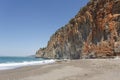 Beautiful sand and pebble beach behind red rock Royalty Free Stock Photo