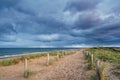 A beautiful sandy path along the ocean. Dark clouds in the sky. North Holland dune reserve, Egmond aan Zee, Netherlands Royalty Free Stock Photo