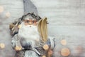 Beautiful santa claus in glasses with skis and gifts on wooden background. Blurred yellow lights on the Santa. Royalty Free Stock Photo