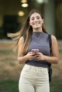 Beautiful satisfied young lady looking at camera texting and standing outside.Joyful confident blond woman staring at Royalty Free Stock Photo