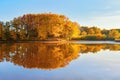 Beautiful scarlet, yellow, orange trees at the river coast reflect in the water. Unbelievable sunny day. Majestic autumn.