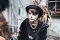 Beautiful scary little girl celebrating halloween. Terrifying black, white half-face makeup and witch costume