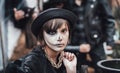 Beautiful scary little girl celebrating halloween. Terrifying black, white half-face makeup and witch costume