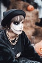 Beautiful scary little girl celebrating halloween. Terrifying black, white half-face makeup and witch costume