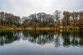 Beautiful scene of a lake reflecting the colorful trees on the shore on a cold autumn day Royalty Free Stock Photo