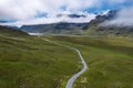 Beautiful scene with small road going into stunning mountains between lush green fields. Connemara, Ireland. Blue cloudy sky.