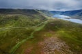 Beautiful scene with small road going into stunning mountains between lush green fields. Connemara, Ireland. Blue cloudy sky.