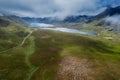 Beautiful scene with small road going into stunning mountains between lush green fields. Connemara, Ireland. Blue cloudy sky.