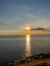 A beautiful scene of Sunset in the bank of a river across the blue sky with some black Ã§louds.