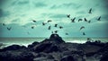 Beautiful scenery of a flock of seagulls taking off from a huge rock formation near the sea Royalty Free Stock Photo