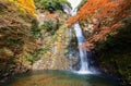 Beautiful scenery of a grand waterfall tumbling down the rocky cliff into a pond surrounded by colorful autumn foliage Royalty Free Stock Photo