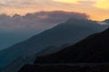 Beautiful scenery of huge rocky mountains in cloudy sky background at a vibrant sunset Royalty Free Stock Photo