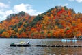 Beautiful scenery of lakeside mountains covered with colorful maple trees & swan boats moored to the floating docks on Lake Towada