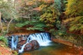 Beautiful scenery of a lovely waterfall tumbling down a rocky stream with colorful autumn foliage