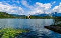 Beautiful scenery of mountain Lake Bled with an island and a church in the foreground white lilies