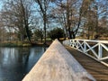 Beautiful scenery of narrow wooden bridge over river in a park during autumn Royalty Free Stock Photo