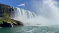 Beautiful scenery of Niagara waterfall flowing near rocky cliffs under blue sky