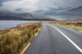 Beautiful scenery and small road by a lake in Connemara, Ireland. Mountains and cloudy sky in the background. Travel and Royalty Free Stock Photo