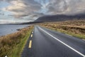 Beautiful scenery and small road by a lake in Connemara, Ireland. Mountains and cloudy sky in the background. Travel and Royalty Free Stock Photo