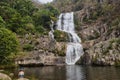 Beautiful scenery of a waterfall flowing into the river in the middle of a rock formation