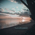 Beautiful scenery of a white rafting boat at the sandy beach of Moorea island during a cloudy sunset