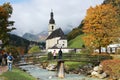 Beautiful scenery of a wooden bridge over a stream in front of a church with foggy mountains in the background Royalty Free Stock Photo