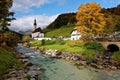 Beautiful scenery of a wooden bridge over a stream in front of a church with foggy mountains in the background Royalty Free Stock Photo