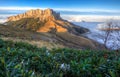 Beautiful scenic autumn landscape of majestic Bolshoy Tkhach rocky mountain peak under blue sky at sunset above white shroud of lo