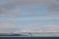 beautiful scenic landscape with snow-covered hills, water and cloudy sky, iceland,