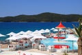 Beautiful scenic summer beach view, white and red parasols near the luxury pool. White fashion deckchairs on the beach by the sea