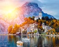 Beautiful scenic sunset over Austrian alps lake. Boats, yachts in the sunlight infront of church on the rock with clouds Royalty Free Stock Photo