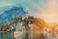 Beautiful scenic sunset over Austrian alps lake. Boats, yachts in the sunlight infront of church on the rock with clouds over Royalty Free Stock Photo