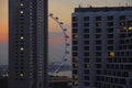 A beautiful scenic view of Singapore flyer attraction behind building blocks under a sunset orange sky evening