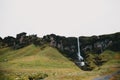 beautiful scenic view of waterfall, rocks and green slopes