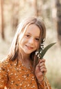 Beautiful school-age girl with lily of the valley flowers in her hand. Summer, sunset Royalty Free Stock Photo