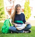 Beautiful school or college girl sitting on the grass with books and bag studying in a park. Royalty Free Stock Photo