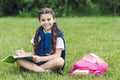 beautiful schoolgirl doing homework while sitting on grass